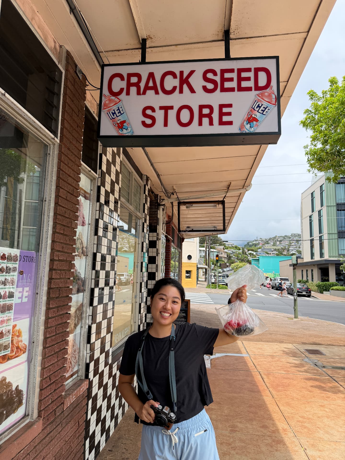 A happy guest with a fresh bag of crack seed outside the Crack Seed Store
